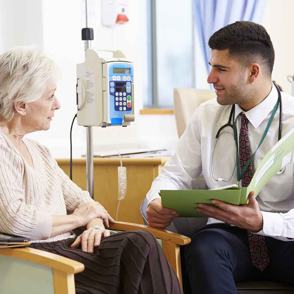 Woman Having Chemotherapy With Doctor Looking At Notes